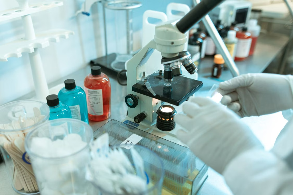 Teknisi laboratorium melakukan penelitian menggunakan mikroskop